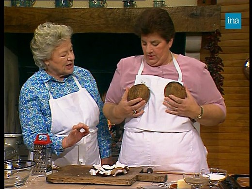🐟🥥 LE BAR À L’EXOTIQUE 🐟🥥. Maïté, flanquée de son acolyte Micheline, nous donne la recette du bar à la noix de coco. Il faut un poisson entier, du citron vert et une noix de coco fraîche. Après avoir patiemment râpé la chair de coco qui servira à confectionner la panure, on fait frire le poisson avec le jus de coco et des ananas. Maïté se confectionne un soutien-gorge avec les coques. C’est prêt, dégustez !! | INA