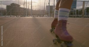 Two women in funky colorful outfits have fun on rollerblades. Best friend laughing, holding hands and turning around. Free spirits and souls experience freedom and youth together.