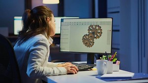 Tired woman architect working on modern cad program overtime sitting at desk in start-up office. Industrial female engineer studying prototype idea on pc showing cad software on device display