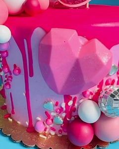 #glambarbiecake Available for pre-order now at www.thesugarbakery.com (Pink colored vanilla buttercream dripped in pink colored white chocolate. Decorated with white chocolate hearts, pink sprinkles and sparkles, ornamental disco balls and pom-poms, rock candy ring and a Barbie topper. You select the inside cake flavor. Personalization feature on a fondant plaque.) | Sugar Bakery | Facebook