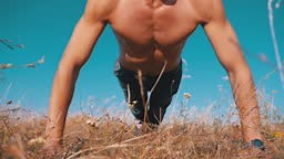 Young Athletic Man with a Bare Torso Performs Pushups on Nature. Slow...