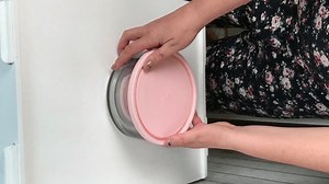 clip-3469123161-woman-examines-glass-food-containers-plastic-lids