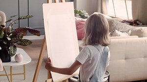 Rear View Of Little Blonde Girl Painting On The Lectern Next To The Window At Home | Free Stock Video Footage