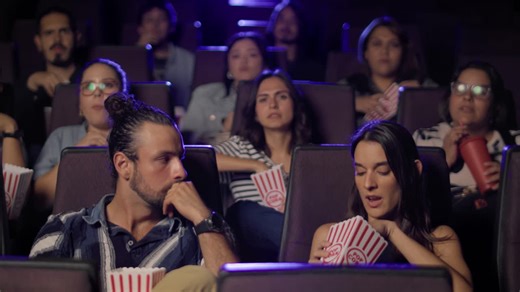 People watching a scary movie in a theater with popcorn - Free Stock Video