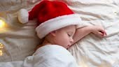 Cute Sleeping Boy in Santa Claus Hat Lying in Bed at Home. Christmas...