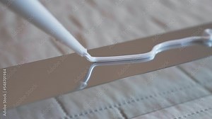 Top view shot of white glue applying on metal profile surface, workman applying sealant in zig zag for further installing. Repairing adhesive glue for fixing different types of surface, industrial