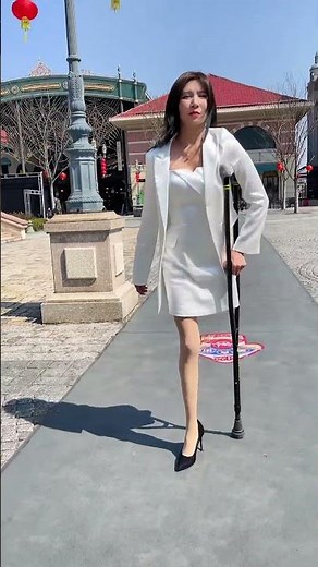 Rika SAK amputee in white dress using one crutch