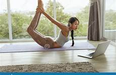 yoga asian stretching training girl computer using body woman practices mat pose watching bow exercise beautiful shutterstock