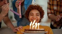Retrato sorridente de aniversariante afro-americana com bolo nas mãos olha para velas acesas faz um