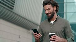 Man holding a cup of coffee and browsing smartphone. Businessman Typing Messages on his Smartphone and drinking hot Coffee