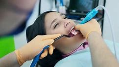 Latina Patient Receiving Ultrasonic Teeth Cleaning on Left Teeth, Laptop X-Ray
