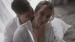 a man is kissing the neck of a woman in a white robe