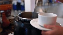Close-up of hands serving hot soup from large pots in a buffet, emphasizing fresh and homemade cuisine.