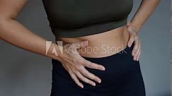 Stomach ache, bloating, flatulence, abdominal distension, colic, heaviness, digestive disorders. A young woman holding her stomach with her hands on a dark grey background. Overeating, overweight