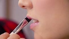 Extreme close up of the female lips. Professional makeup artist applying lip gloss on the model's lips