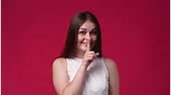 4k video of one girl showing silence sign on red background. Concept...