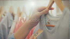 Fashion hangers. In stylish accessories store, young woman in trendy clothes pays attention the clothing reuse signs. He enthusiastically follows fashion trends and holds a tag with a recycling symbol