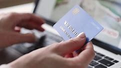 Female hands of cardholder holding credit card making e bank online payment. Woman consumer paying for purchase in web store using laptop technology. Ecommerce website payments concept. Close up view