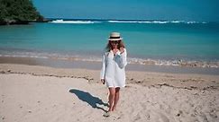 Blonde slim woman in airy pareo walking down ocean sandy beach admiring mountains in evening. Tourism, travel, tropical vacation concept. Girl in romantic outlook enjoying sea coast, waves.