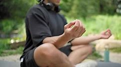 Manos de cerca, joven afroamericano, hombre de espiritualidad meditando asana de yoga sentado en un parque