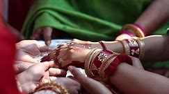 Premium stock video - Indian women wearing vibrant and colourful attire doing a traditional bengali wedding ritual with henna hands and milk