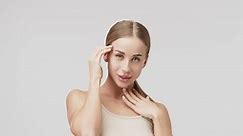 Portrait of a young beautiful woman with smooth healthy skin, she gently touches her face. Cosmetics, spa and skin care products advertising concept.