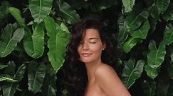 Beauty spa portrait of young brunette girl with perfect skin, natural make-up and healthy shiny hair in front the jungle among exotic plants. High quality skin care and natural cosmetics 4k slow