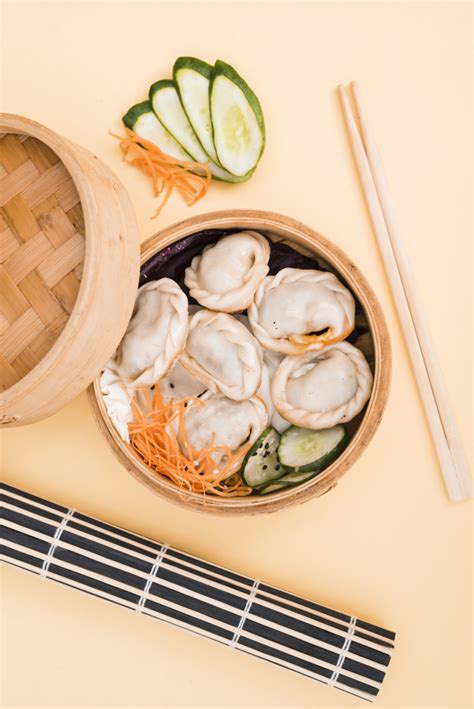 Eat with your fingers or chopsticks at your next chinese new year party, or any time. Free Photo | Chinese dumpling and salad in a bamboo steamer box on colored backdrop with chopsticks