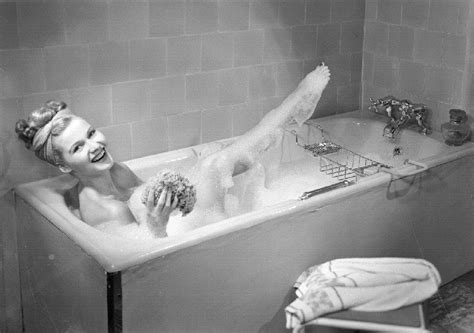 Treating yourself with a hot or warm bath can feel like the height of luxury. a woman takes a bubble bath in her bathtub | 1950 | # ...