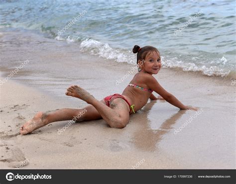 Dit kan vanuit een naturistische. Een klein meisje nemen sunbathes op het strand in de buurt ...