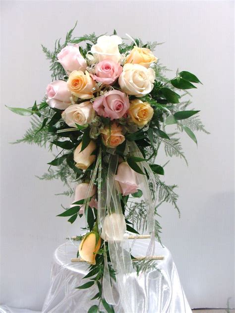 A cascading bouquet is an arrangement of flowers that literally cascades from the bride's hands, creating a natural, trailing effect. Cascading Wedding Bouquet with Peach, white and pink roses ...