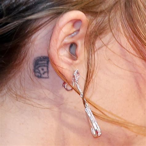 Dakota johnson has a small black ink tattoo behind her right ear. Dakota Johnson Behind Ear Tattoo | Steal Her Style