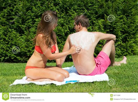 Sun exposure is a risk factor for skin cancer and photoaging. Woman Applying Suntan Lotion On Man S Back Stock Photo ...