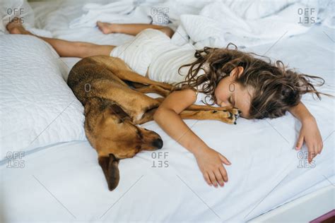 Girl sprawled out on bed sleeping with her pet dog stock photo - OFFSET
