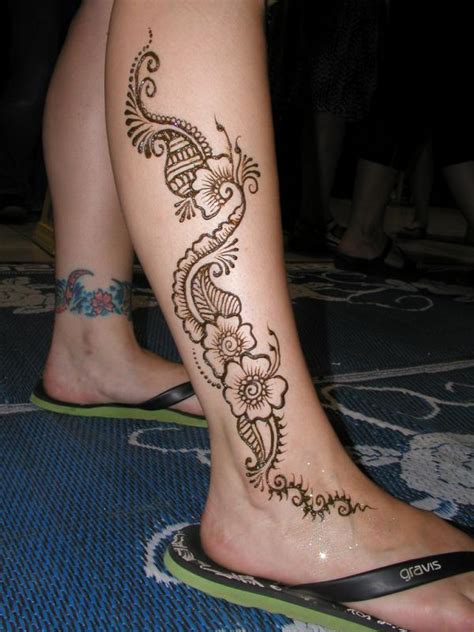 One foot has a pretty, patterned flower while the other design has a bold flower with leaves. 22 Superlative Mehndi Tattoo Designs for Ladies - SheIdeas