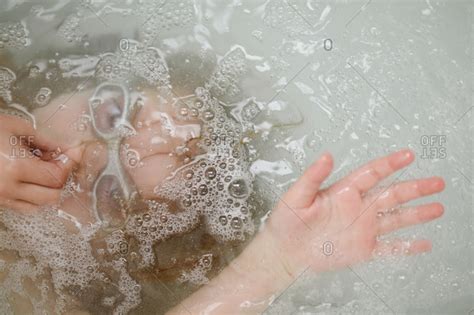 Baby submerged in bath : Girl submerged in tub water stock photo - OFFSET