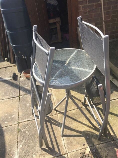 There is a table and a chair in the room. Small garden table with two chairs | in Maidenhead ...