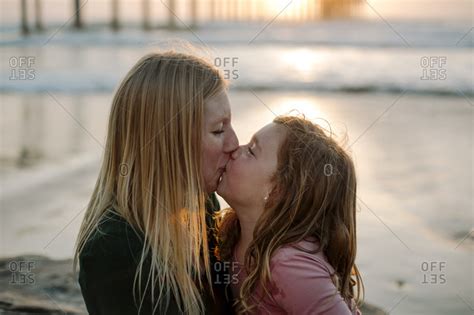 The grimm fairy tale gets a technicolor treatment in disney's first animated feature. Mother and daughter kissing at beach stock photo - OFFSET