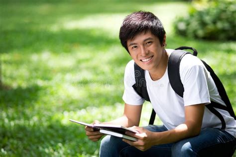 The entire asian college family mourns this loss. Young handsome Asian student with laptop. And smile in ...
