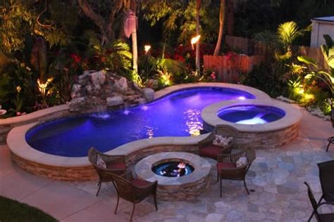 Floral accents showcase vibrant colors and tropical appeal, while traditional backyard torches add classic island charm. A beautiful Elevated Pool at night with tiki torches ...