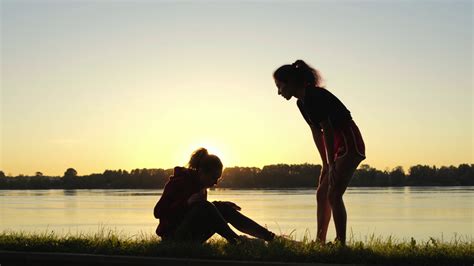 Silhouette of girl giving helping hand to her friend during training ...