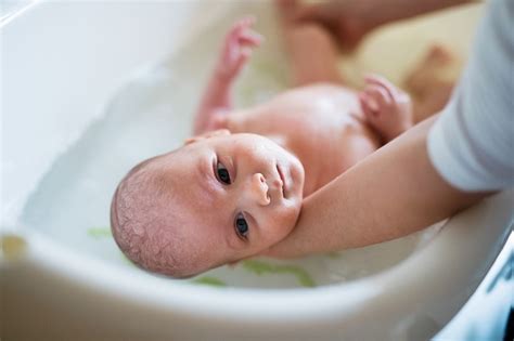 Using a football fold with the palm of. How to Give Bath to a Newborn Baby | Mom Envy Blog