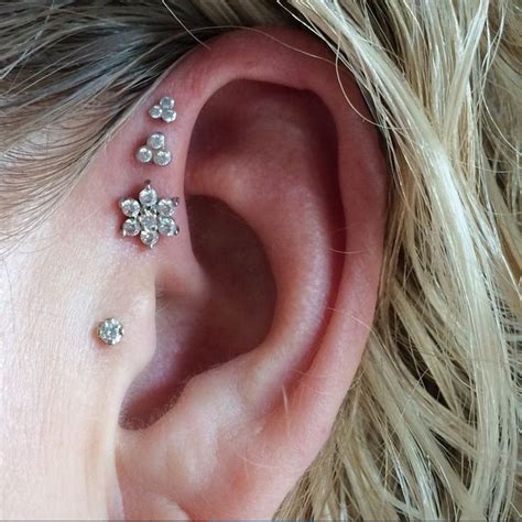 Triple forward helix piercings and tragus piercing. White ...