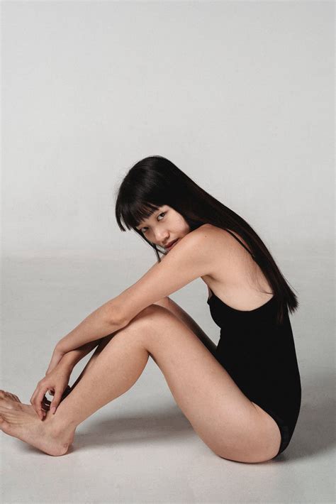 Attractive Asian woman sitting on floor in light studio · Free Stock Photo