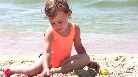 Little girl play with sand on beach - Royalty Free Video
