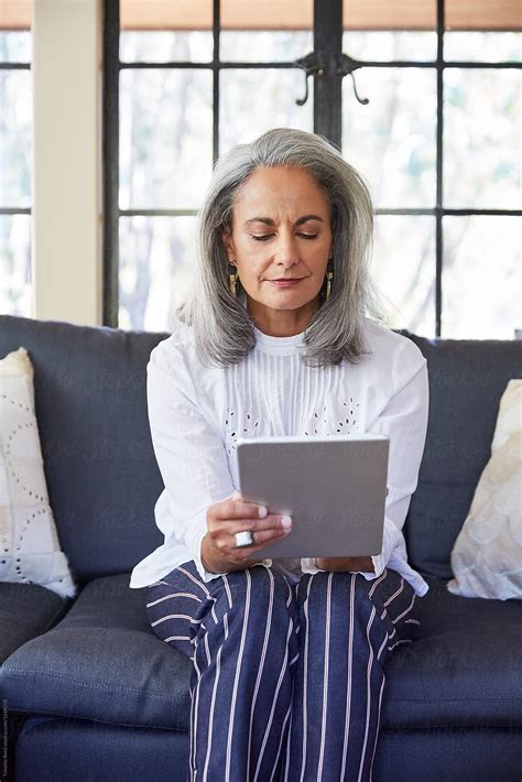 Mature Woman With Grey Hair Using A Digital Tablet In Living Room by ...
