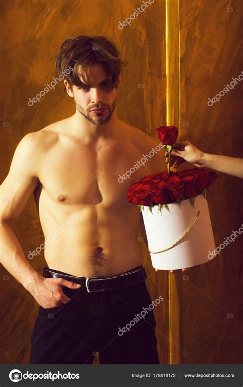 Бородатый мускулистый мужчина с сексуальным телом держит красную ...