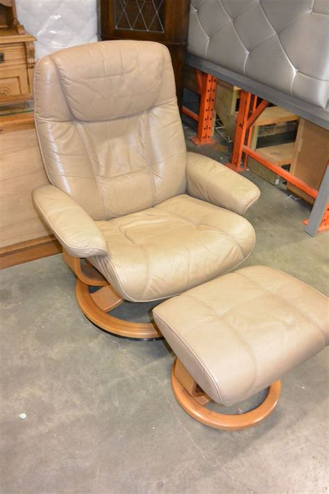 This office chair is supported by a chromed steel base that's equipped with rolling casters. BEIGE LEATHER PALLISER RECLINER CHAIR AND OTTOMAN