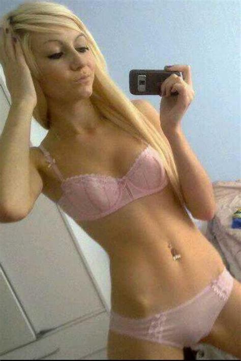 Skinny and tattoed emo girlfriend selfshot. Blonde nymph in pink lingerie shooting a selfie ...