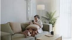 Asian senior woman sitting on couch during using mobile and credit...